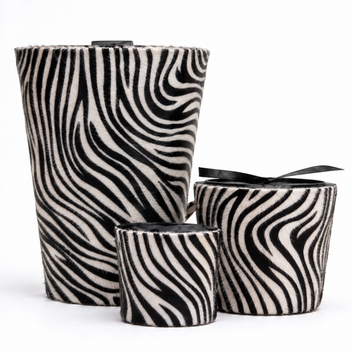 Three zebra-print fuzzy cylindrical containers or candle holders with black ribbon accents, arranged on a white background.